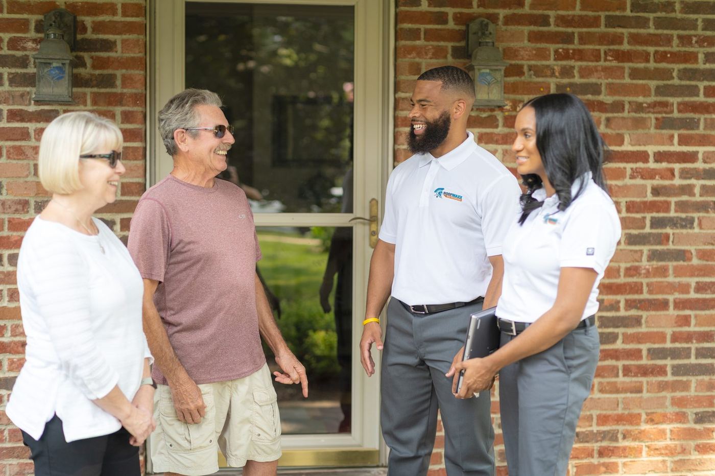 Roof Maxx technician with smiling homeowners